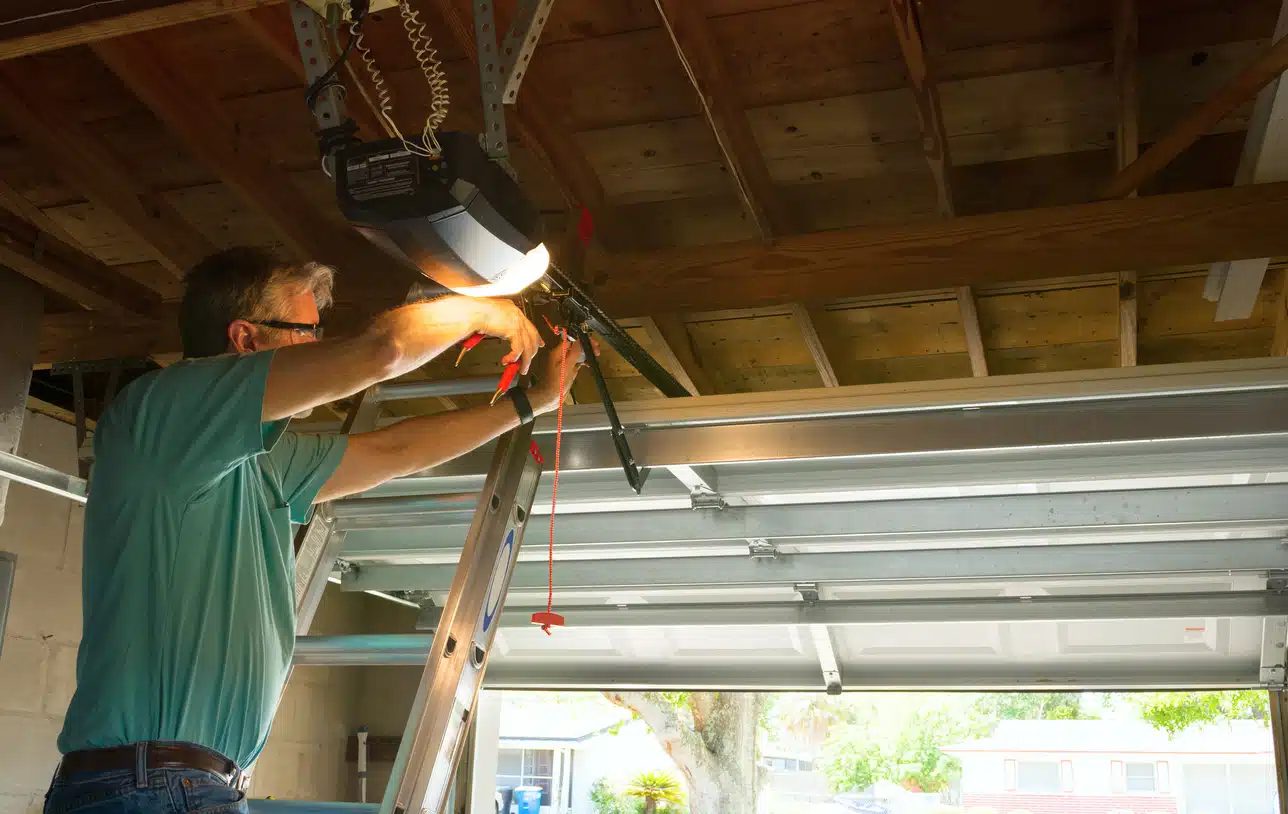 Titletown Garage Door technician diagnosing an overhead opener from a ladder